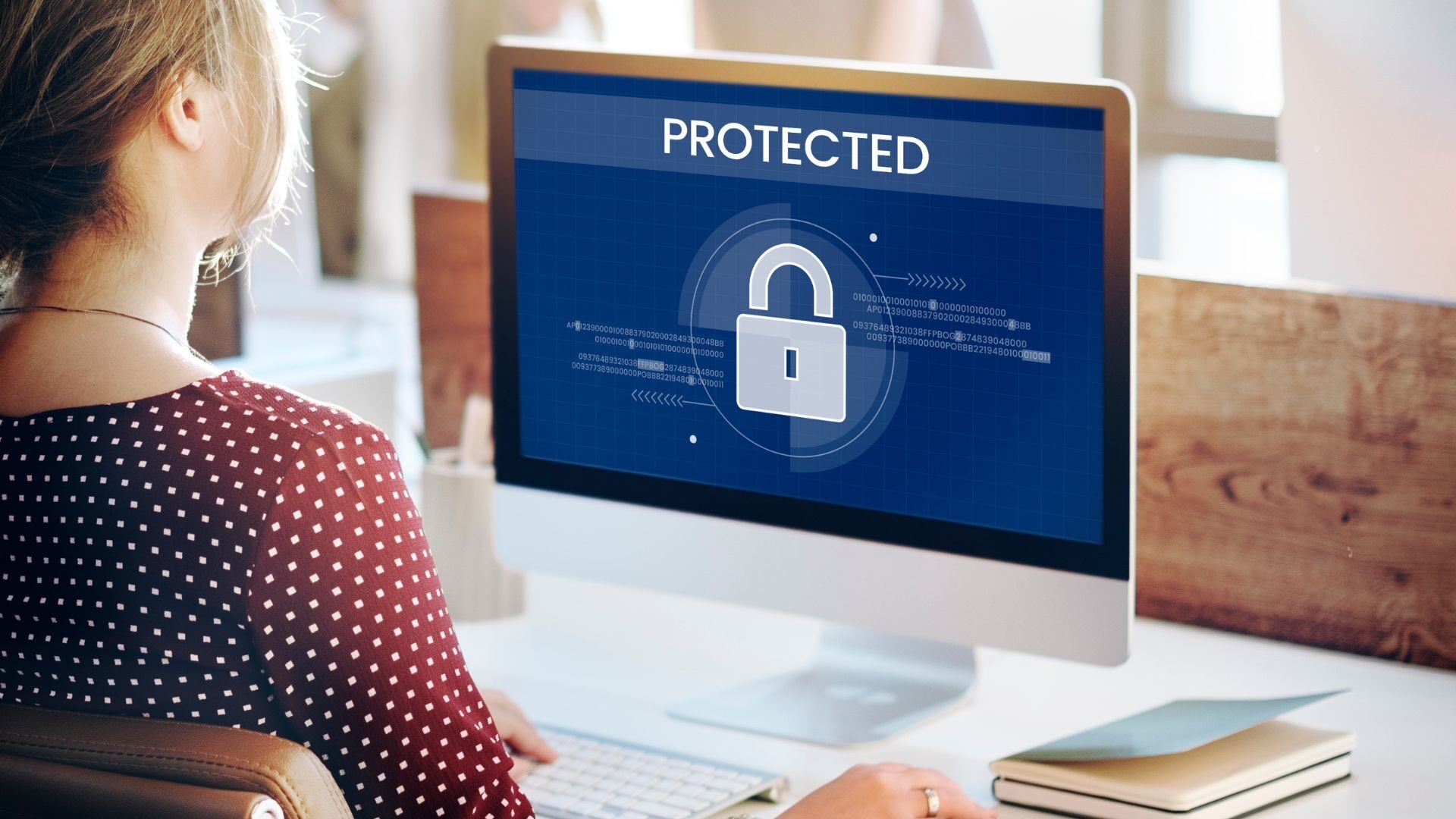 Protección de datos — mujer frente a monitor con candado y mensaje Protected
