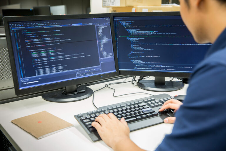 Ley de datos personales — profesional TI revisando código en dos monitores
