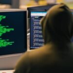 grupo FamousSparrow — persona con capucha frente a monitores con código