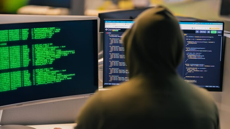 grupo FamousSparrow — persona con capucha frente a monitores con código
